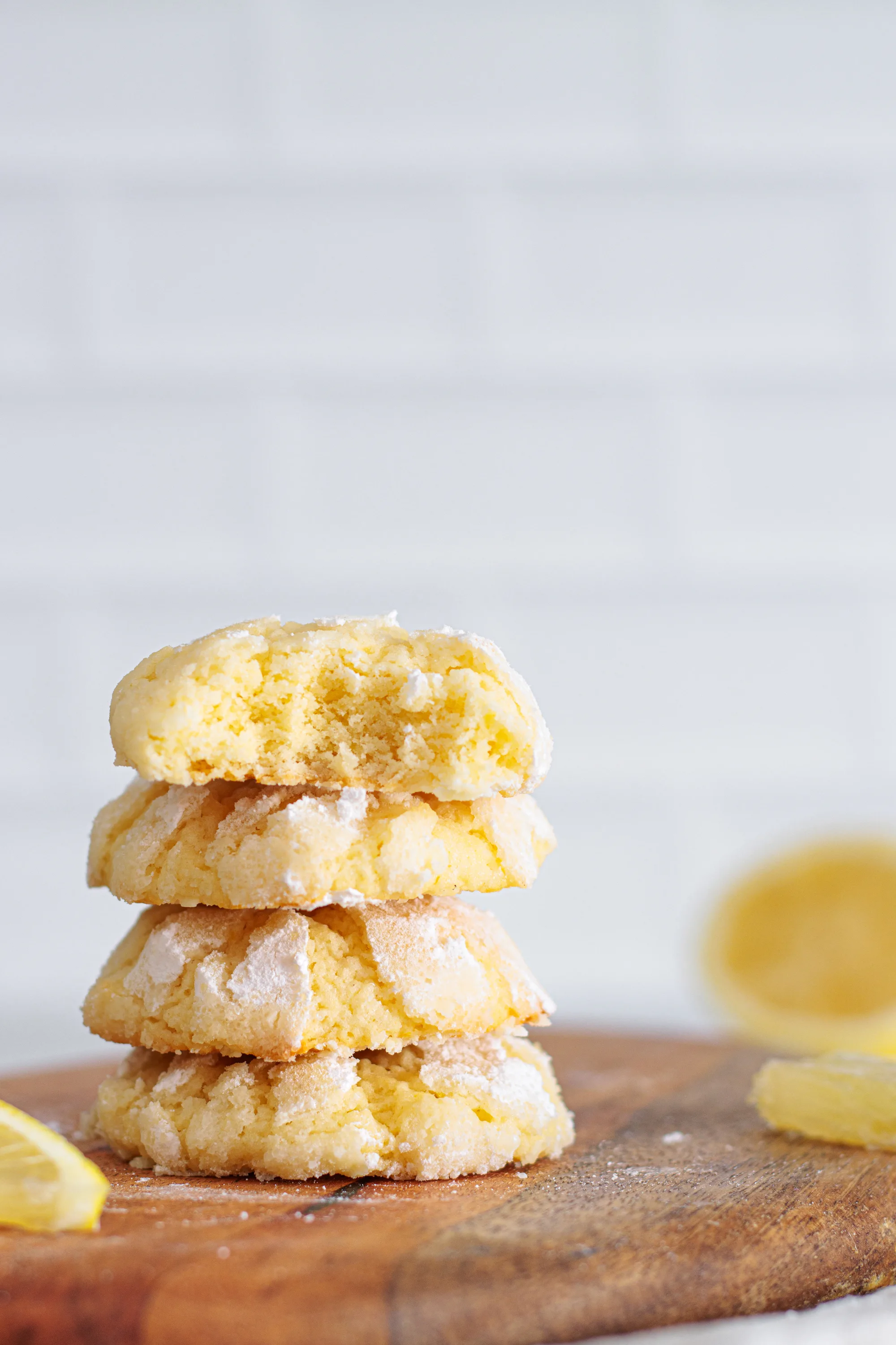 Stack of lemon crinkle cookies with powdered sugar cracks and a soft lemon-colored center